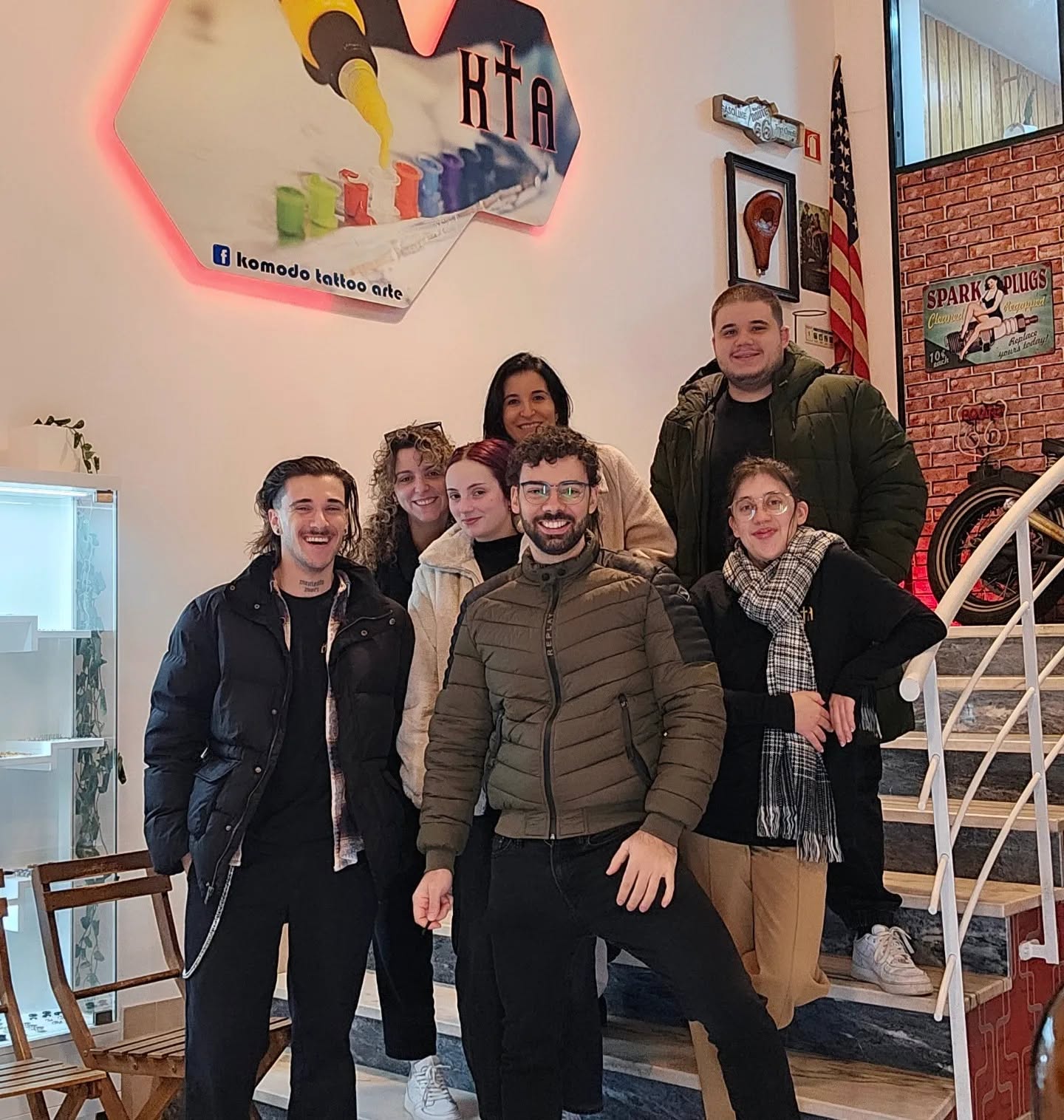 Equipa da KTA reunida na escadaria do estúdio, sob o letreiro luminoso
