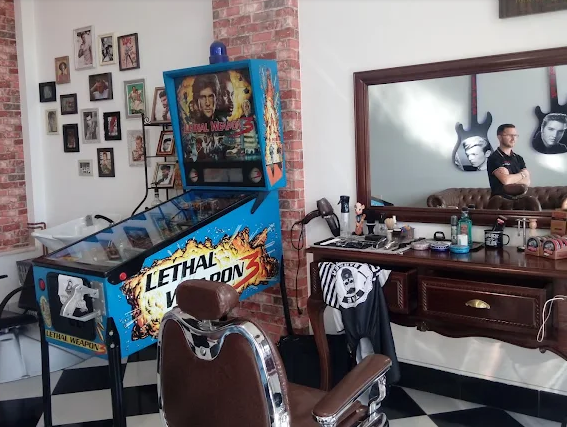 Sala do estúdio com máquina de pinball, cadeira de barbeiro e parede de quadros