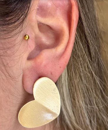 Orelha com piercing dourado colocado na cartilagem