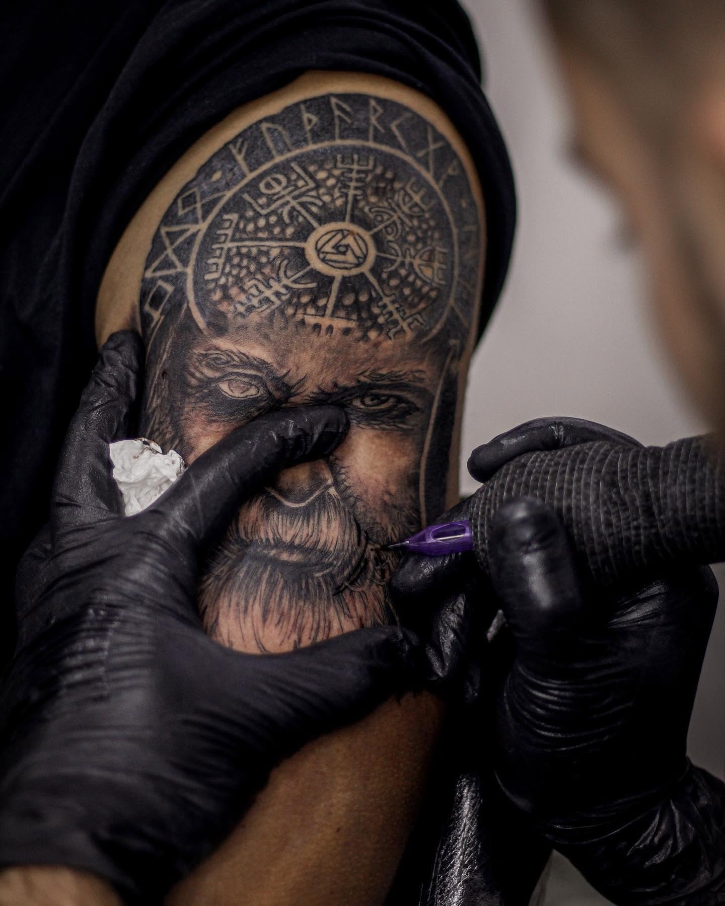 Retrato a ser tatuado, com luvas pretas e a máquina em cima da pele